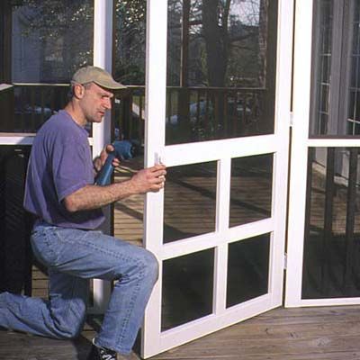 A man installs the screen door.