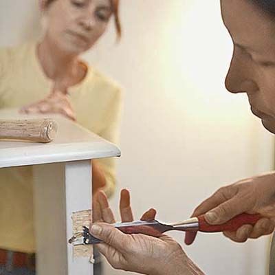 A person prepares the cabinet for new hinges for it's shutter door.