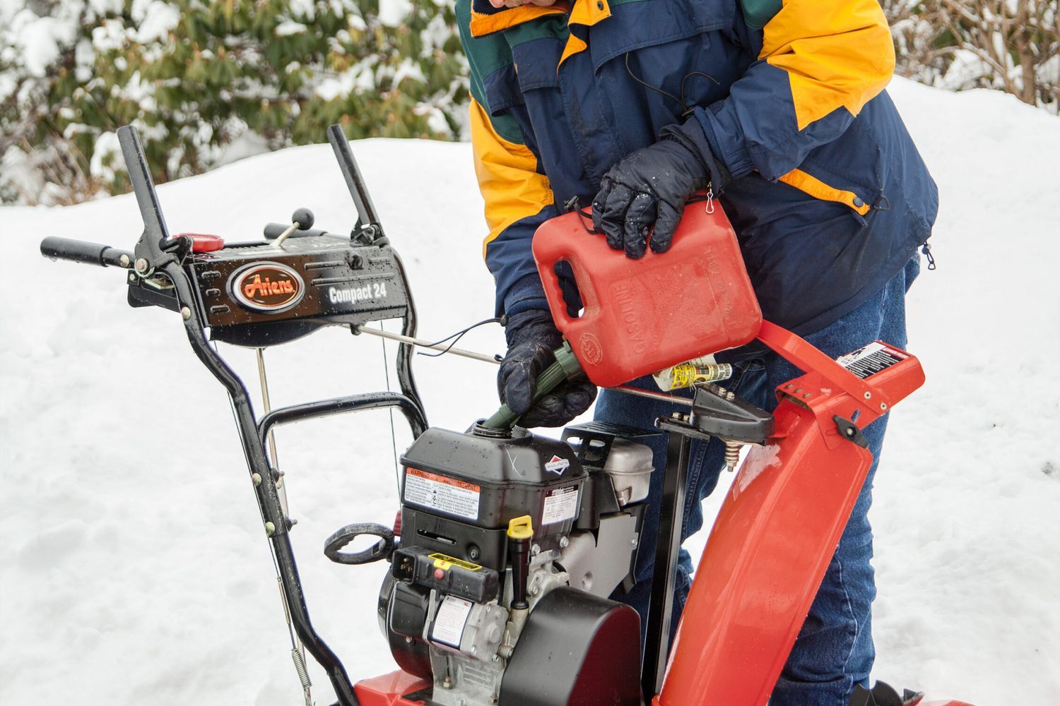 A man filling a snow blower with gas.