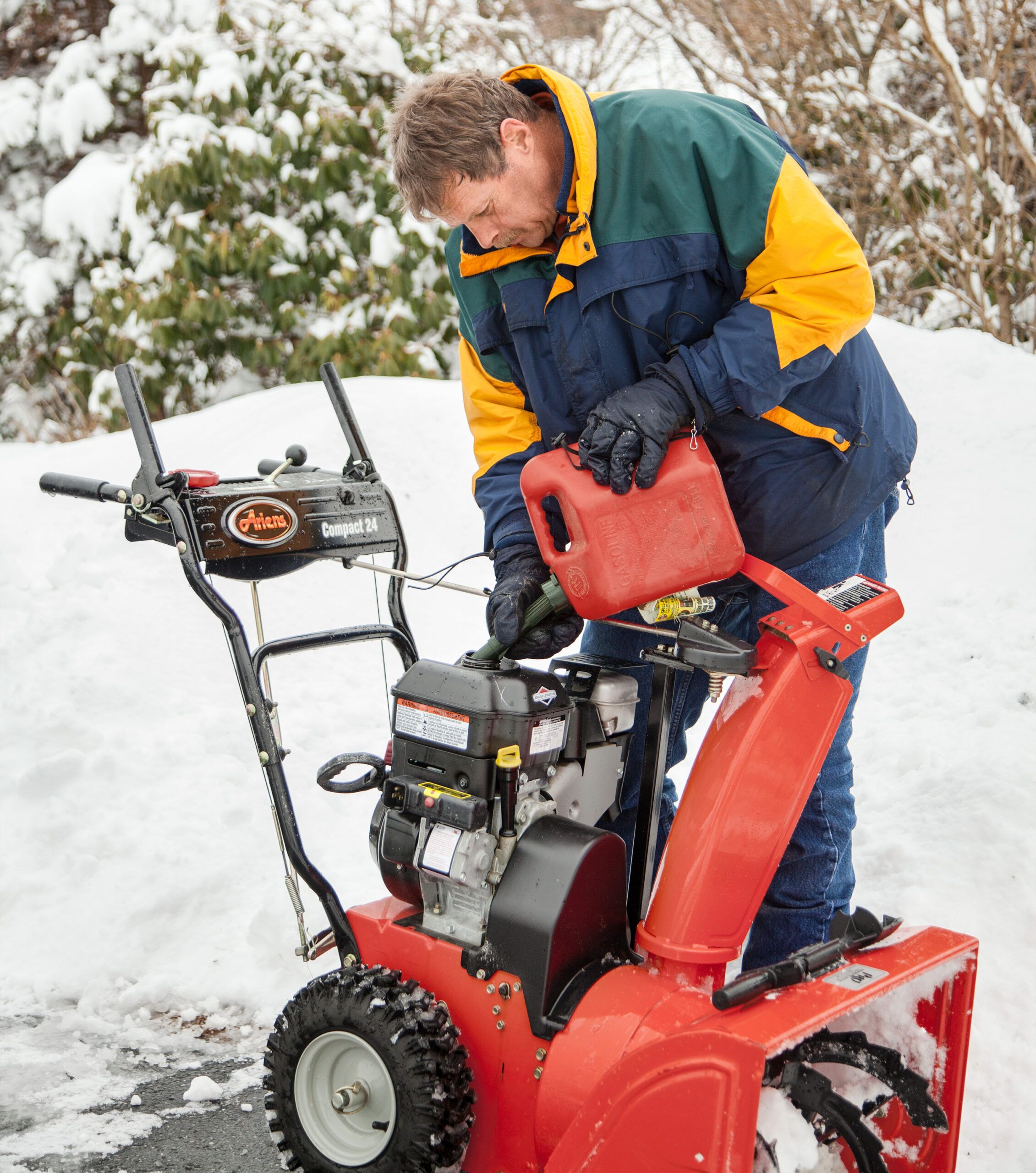 A man filling a snow blower with gas.