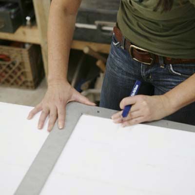 Image of a person measuring and marking desired shelf locations for a DIY stylish bar cabinet. 