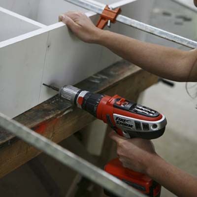 Image of a person driving finish screws through the side of the DIY stylish bar cabinet