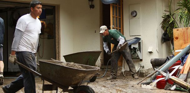 People cleaning up a home after a storm