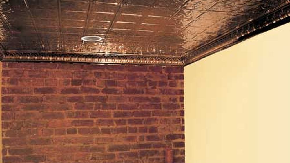 Room with a brick wall and tin ceiling