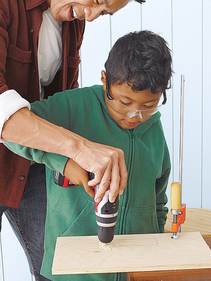 Image of a father teaching his child how to stay safe when doing work in a workshop