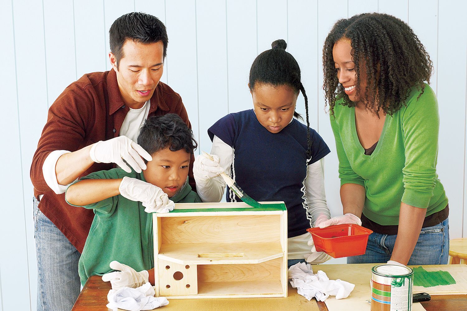 Image of a family working in a workshop together. The parents are teaching their children workshop safety