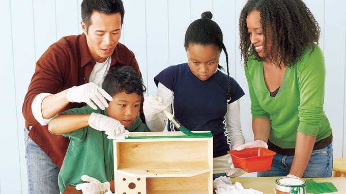 Image of a family working in a workshop together. The parents are teaching their children workshop safety