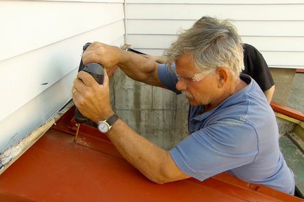 A man using a drill to install bulkhead doors.