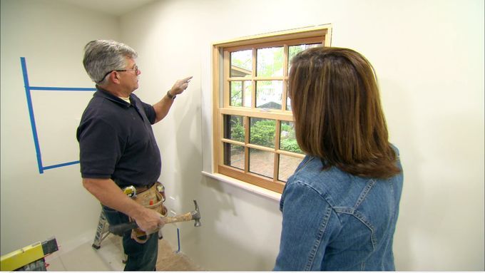 A man working on adding window trim to a window.