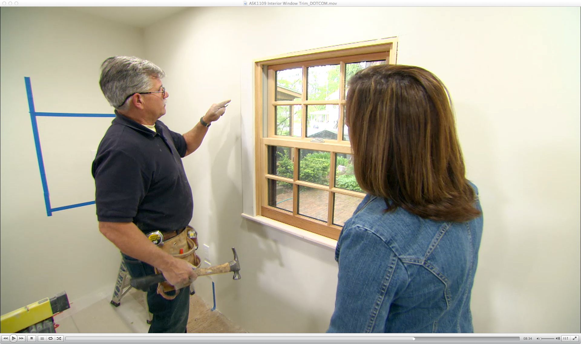 A man working on adding window trim to a window.
