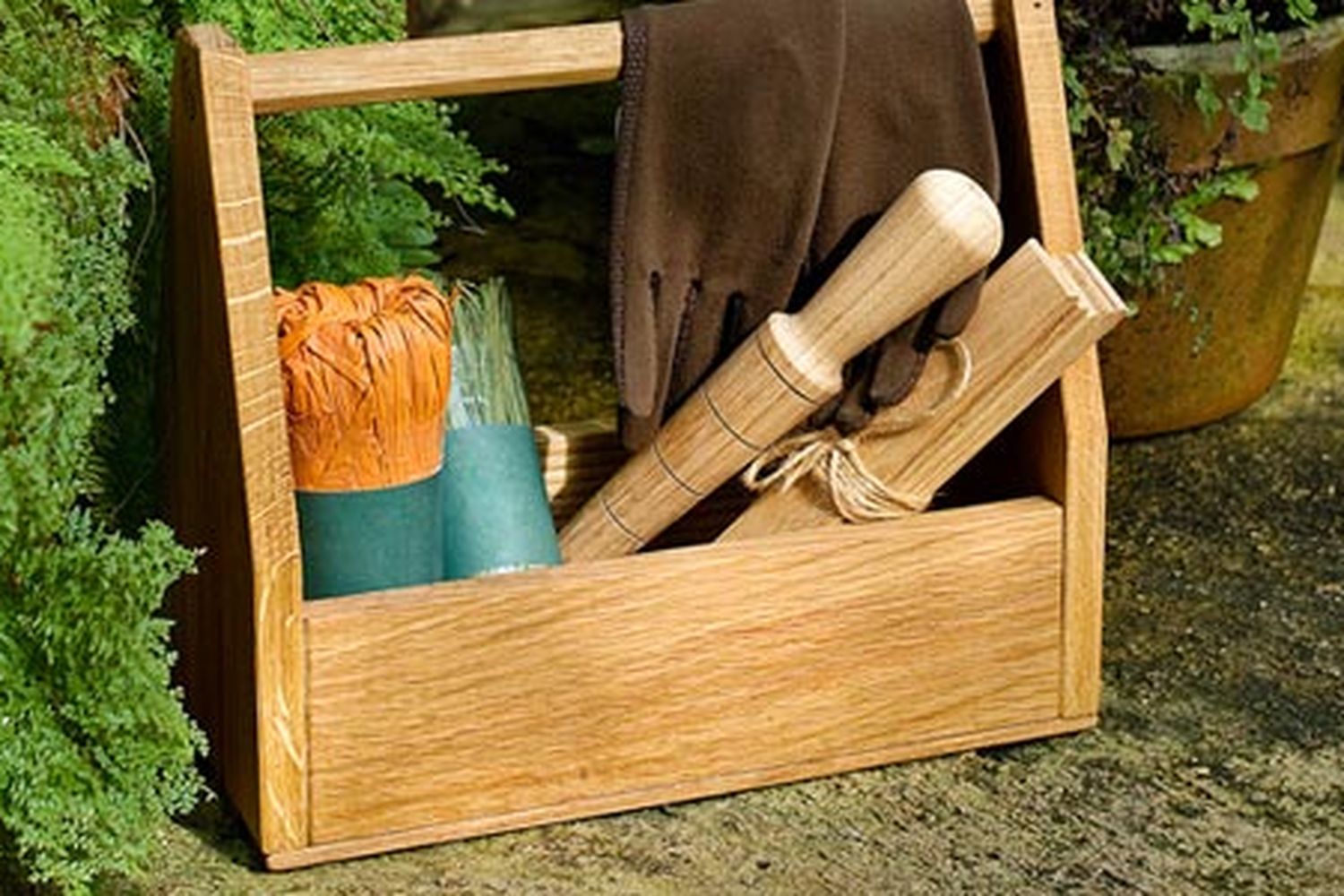 A wooden garden tool-tote with tools resting inside of it.