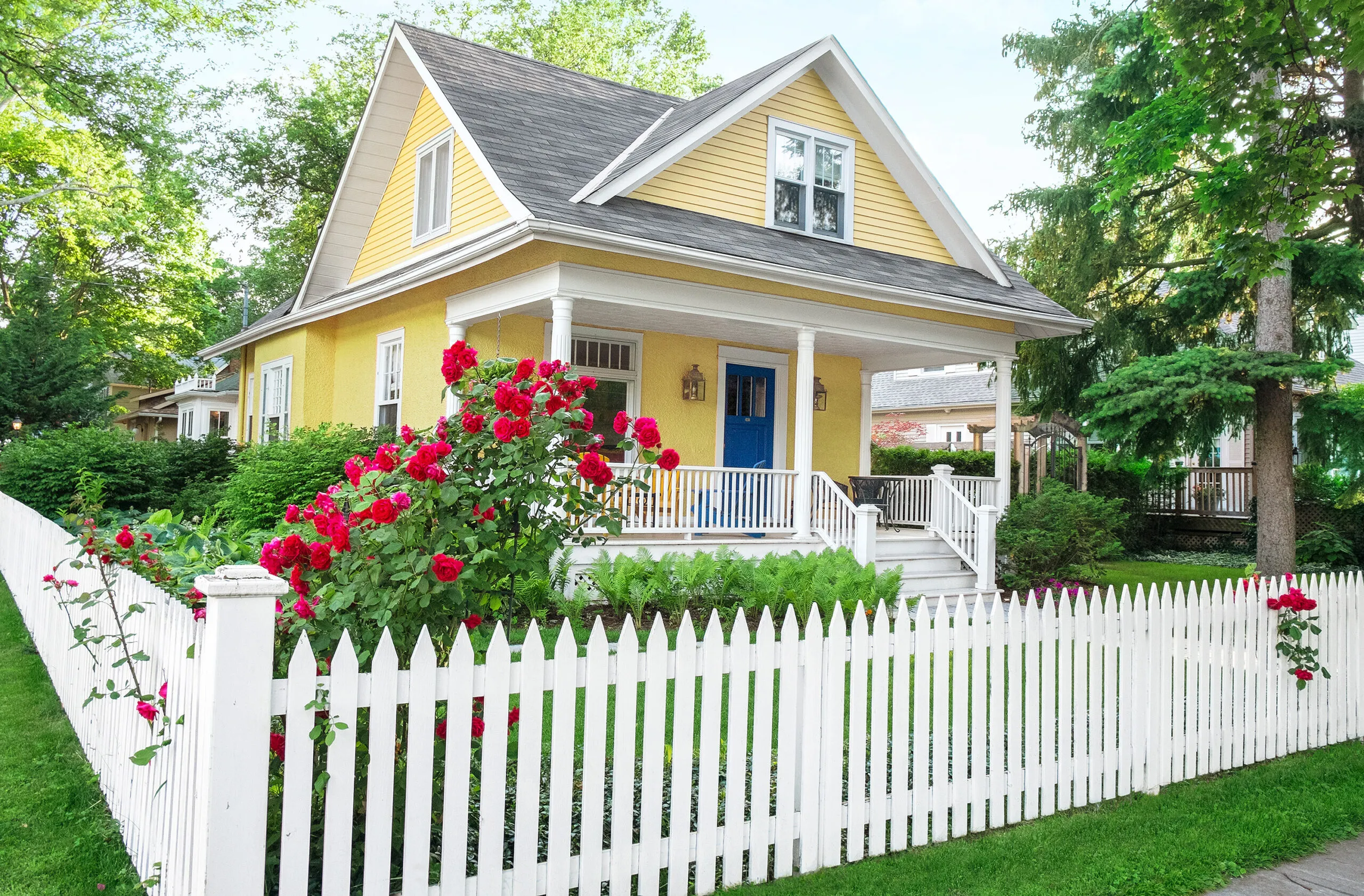 A yellow home with a picket fence.
