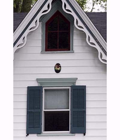 Blue and green Carpenter Gothic style windows on a white Victorian home. 