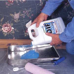 Stripping gel being poured into a metal paint tray.