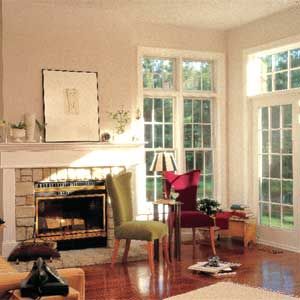 A room with wood windows, a fireplace, and cushioned chairs.