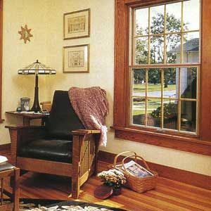 A room with outswing casement windows as well as a cushioned chair and framed pictures.