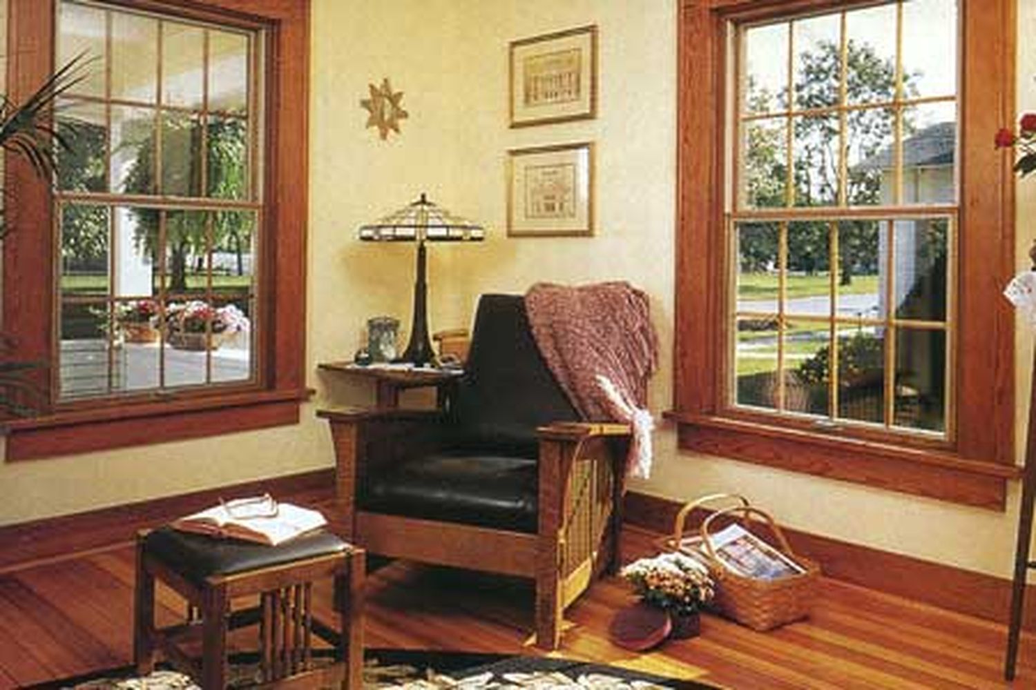 A room with outswing casement windows as well as a cushioned chair and framed pictures.