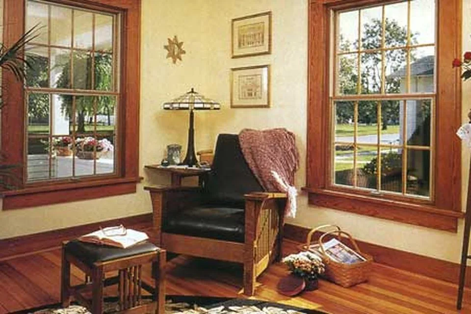 A room with outswing casement windows as well as a cushioned chair and framed pictures.