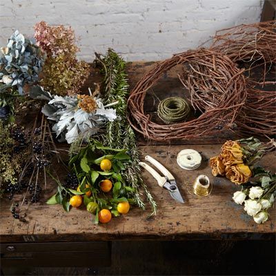 Supplies for wreath making including flowers, clipping tools, and wood.