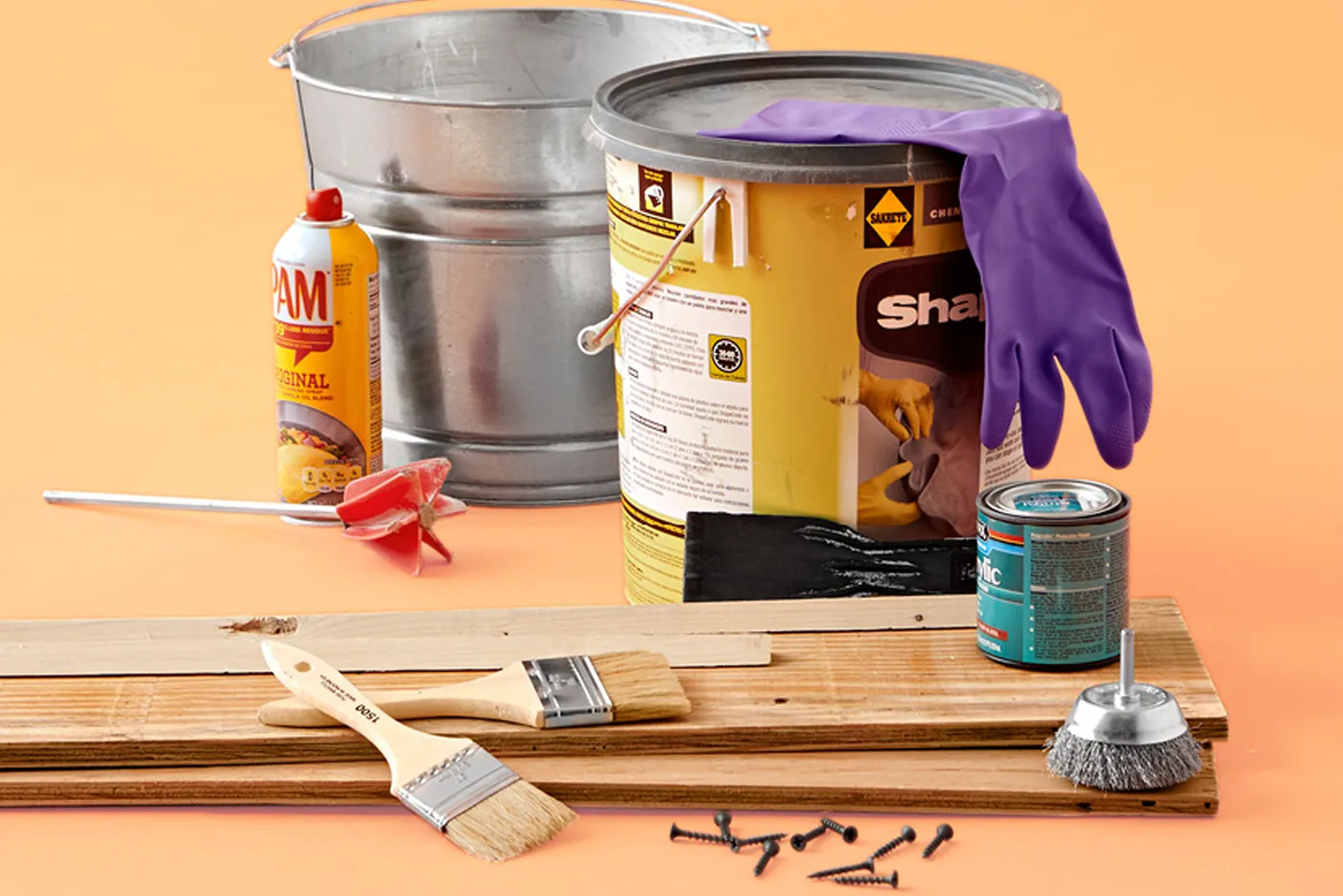 The materials needed to make a concrete umbrella stand such as buckets, concrete, gloves, nails, plywood, mixing tools, and cooking spray.