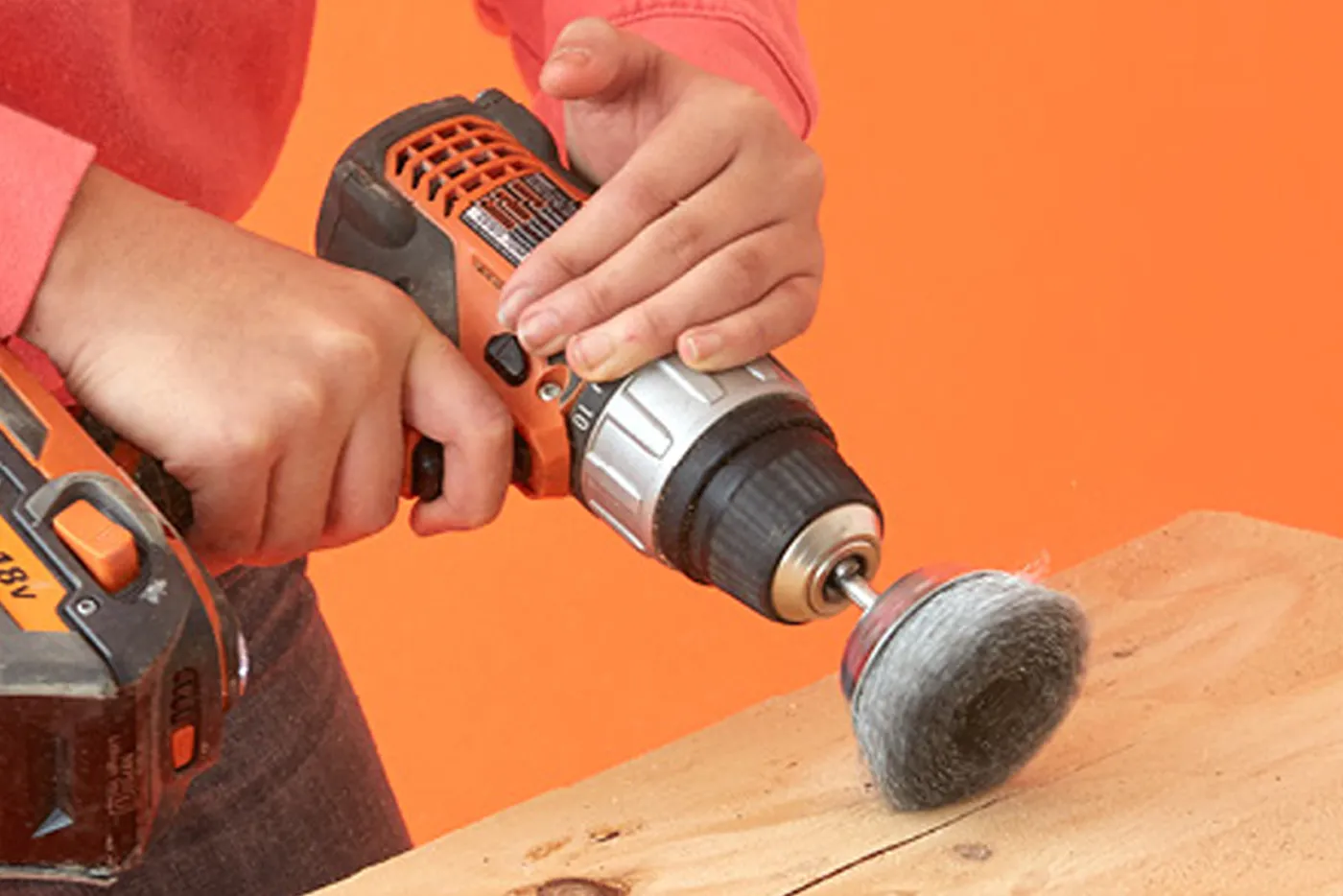 A person using a wire brush to distress plywood.