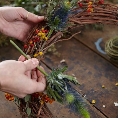 A woman adding flowers and accents to a wreath.