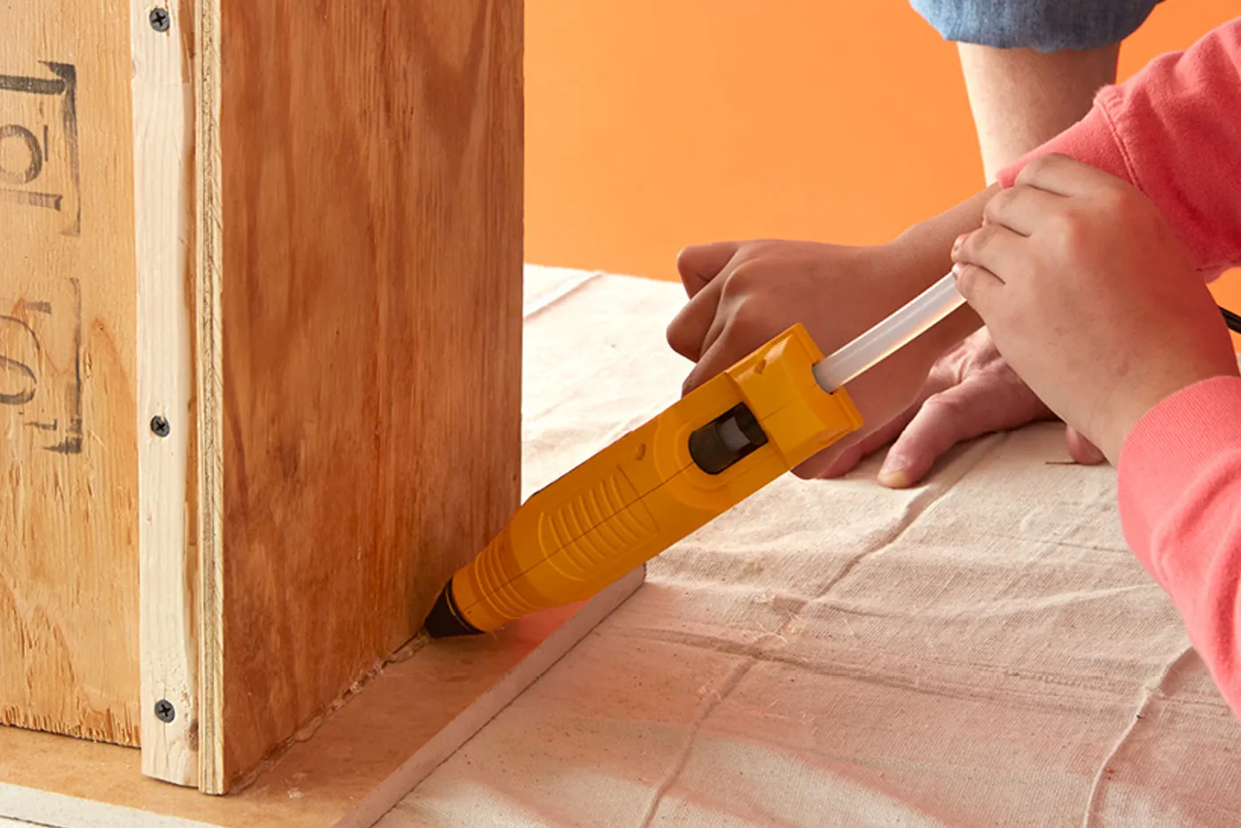 A person using a hot glue gun to attach the form to the base.
