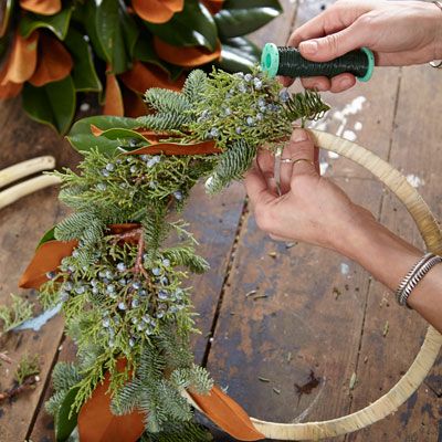 A woman putting the finishing touches on an evergreen wreath.