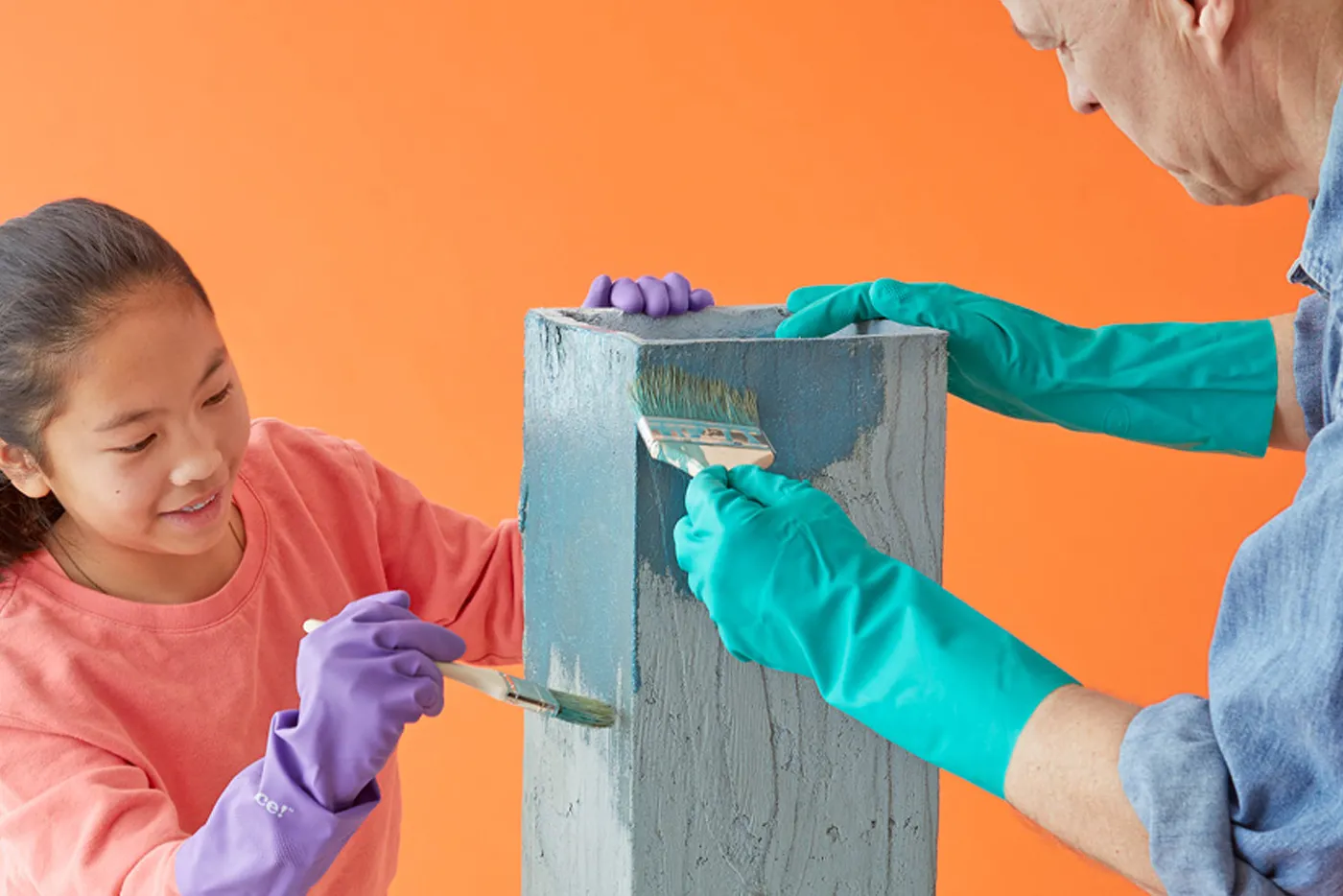 An adult and child together adding dye to the concrete stand to make it colorful.
