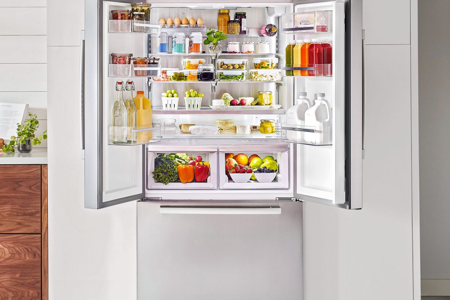 An open stainless steel refrigerator showcases organized shelves filled with fresh produce, beverages, and dairy products, highlighting efficient use of space and energy-efficient storage solutions.