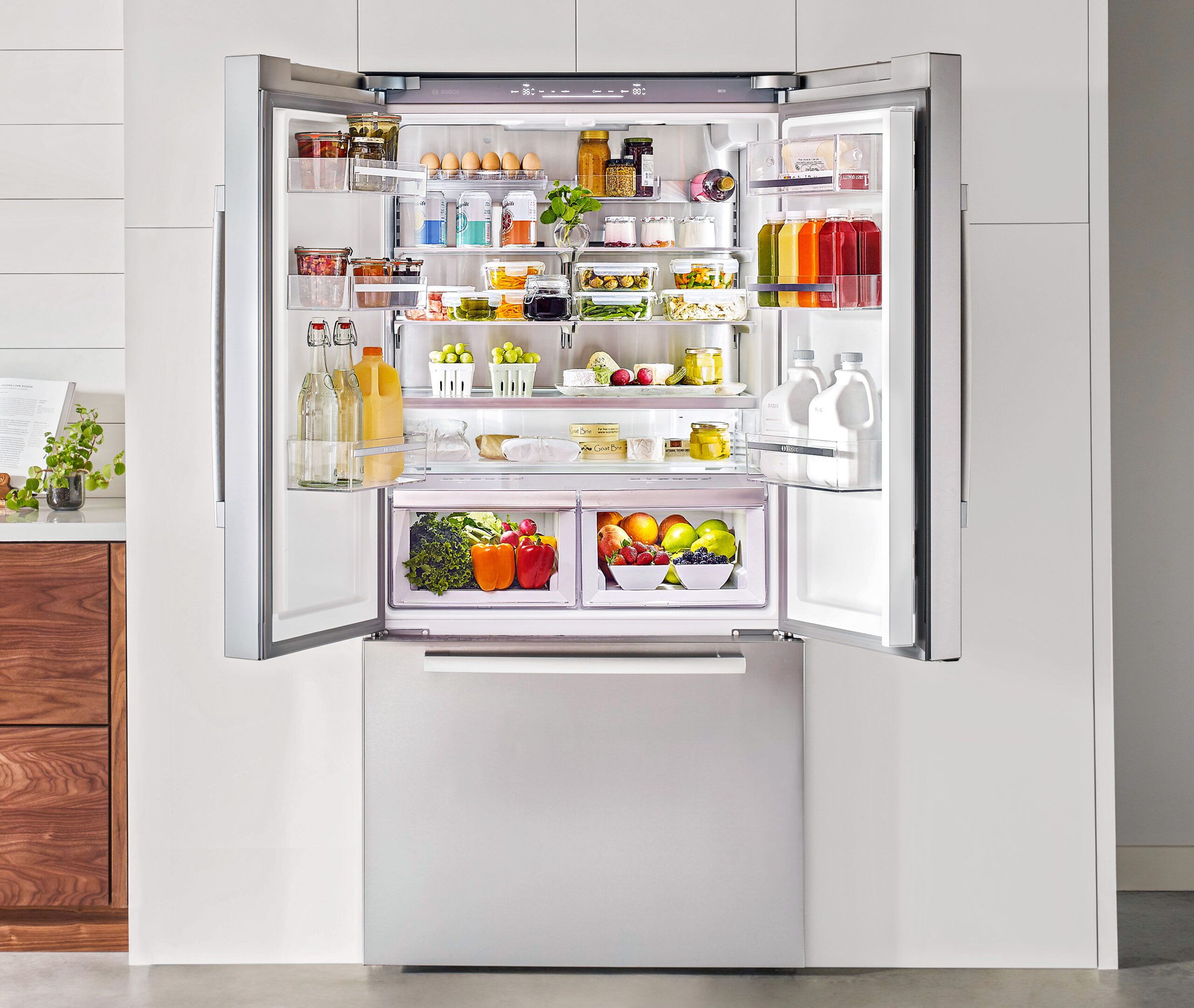 An open stainless steel refrigerator showcases organized shelves filled with fresh produce, beverages, and dairy products, highlighting efficient use of space and energy-efficient storage solutions.