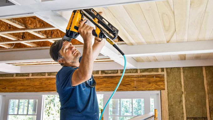 A man using a nail gun to work on replacing a ceiling.