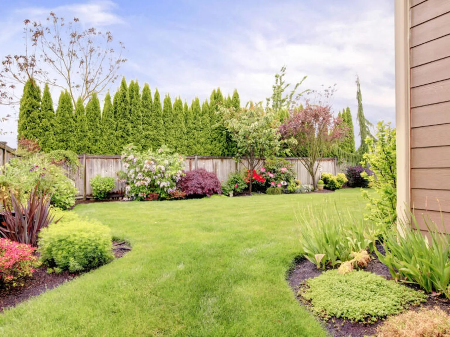 A landscaped yard with multiple gardens and trees.