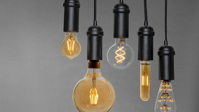 A variety of different types of light bulbs hanging from black cords.