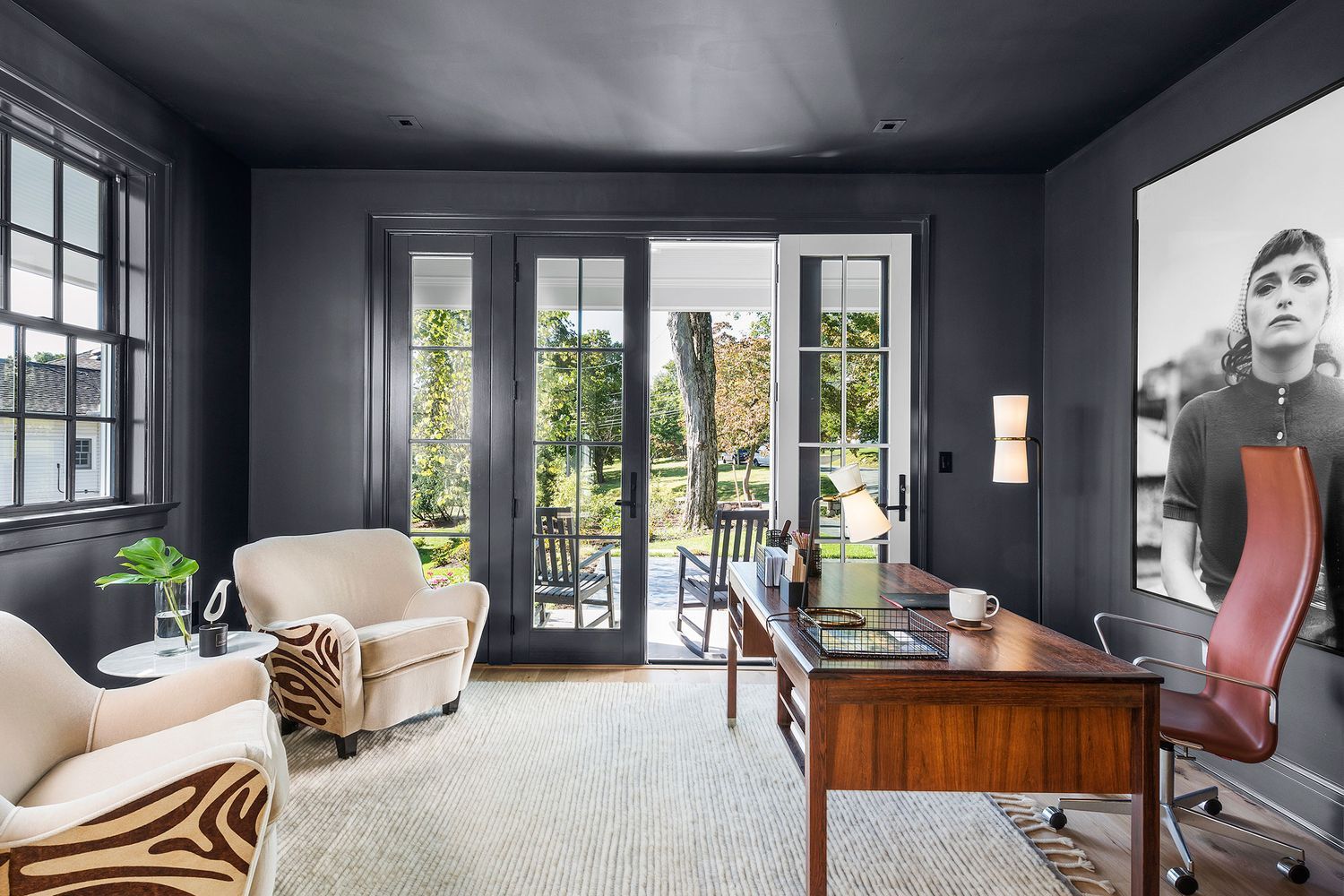 A home office with a desk, chairs, and a framed photo hanging on the wall.