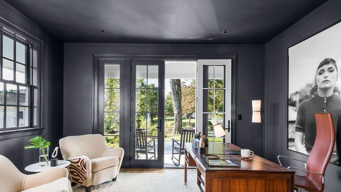 A home office with a desk, chairs, and a framed photo hanging on the wall.