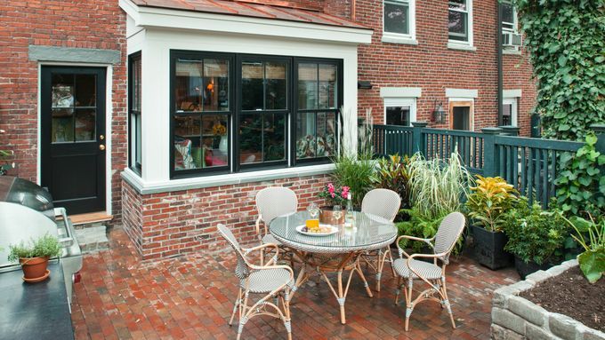 A brick patio decorated with patio furniture and potted plants.