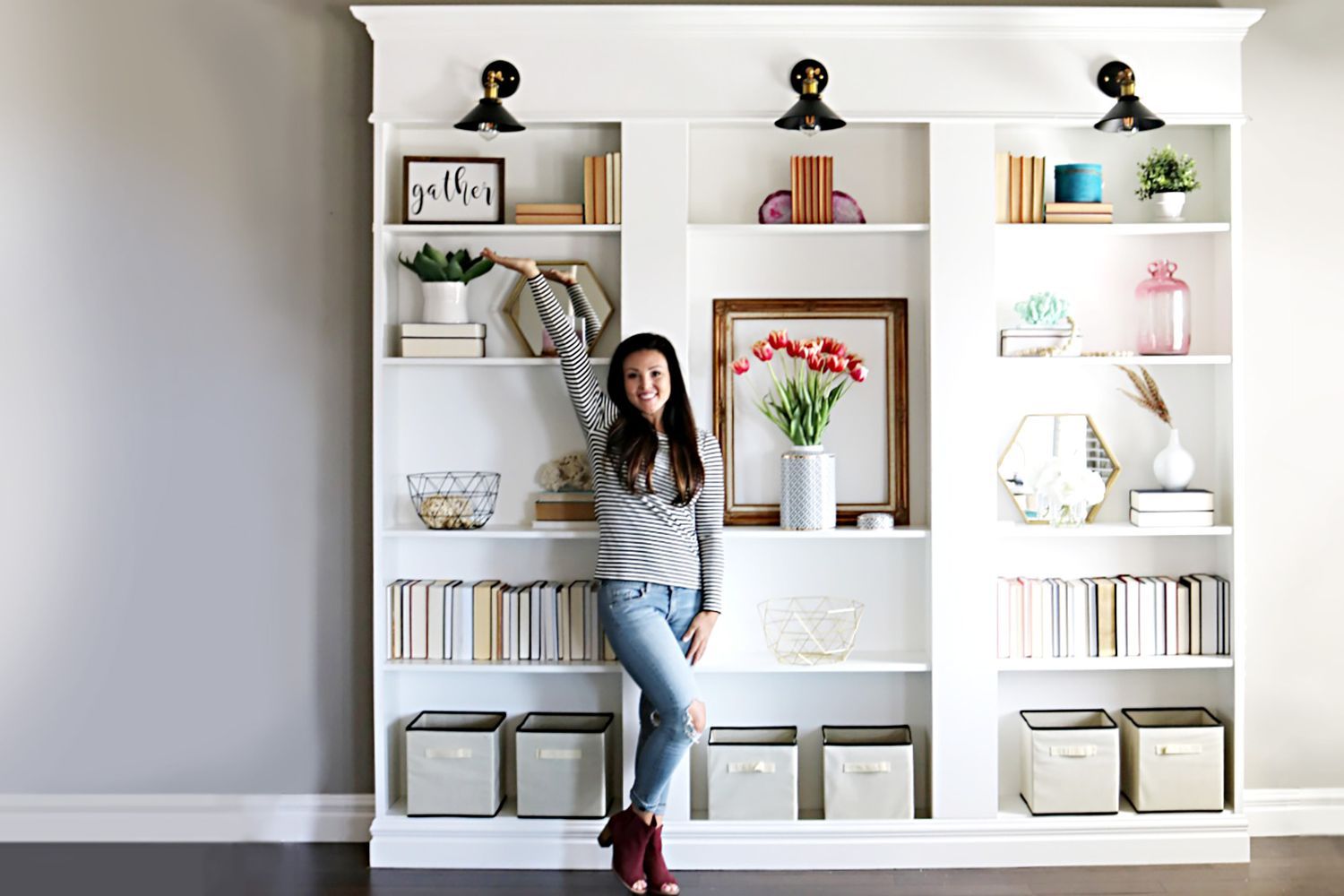A woman posed in front of a built-in bookcase that she made from three IKEA bookcases.