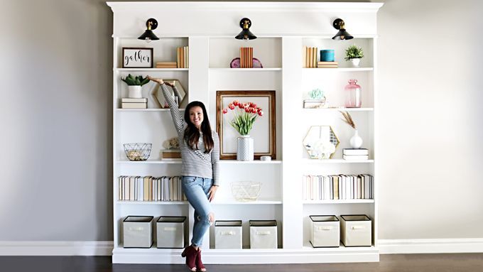 A woman posed in front of a built-in bookcase that she made from three IKEA bookcases.