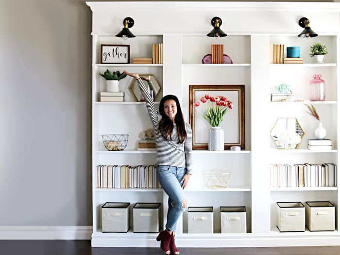 A woman posed in front of a built-in bookcase that she made from three IKEA bookcases.
