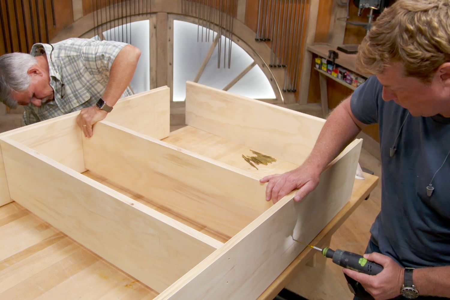 two people working on building a wooden bookshelf.