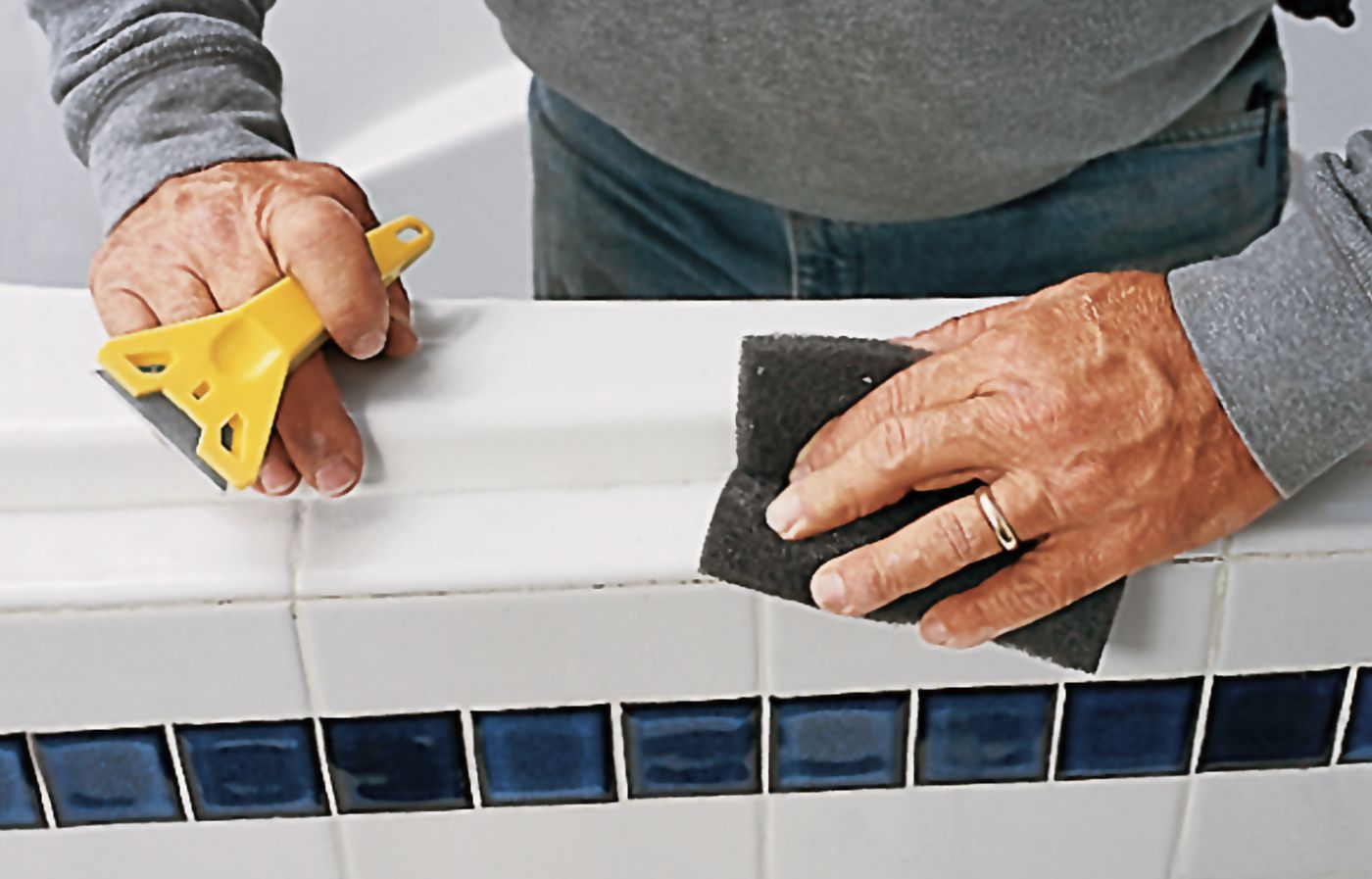 A person cleans the bathtub area before adding new caulk.