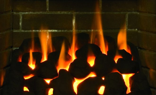 A fire growing in a fireplace.