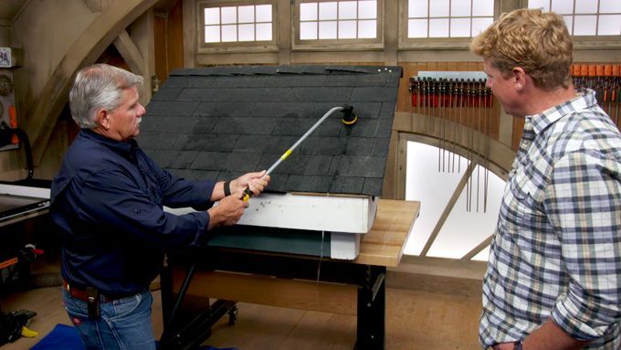 A man using a tool to demonstrate drip edge roofing installation to another man.