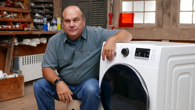 A man sitting beside a heat pump dryer.