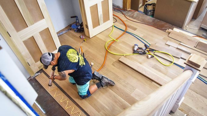 A contractor installing vinyl flooring over tile.