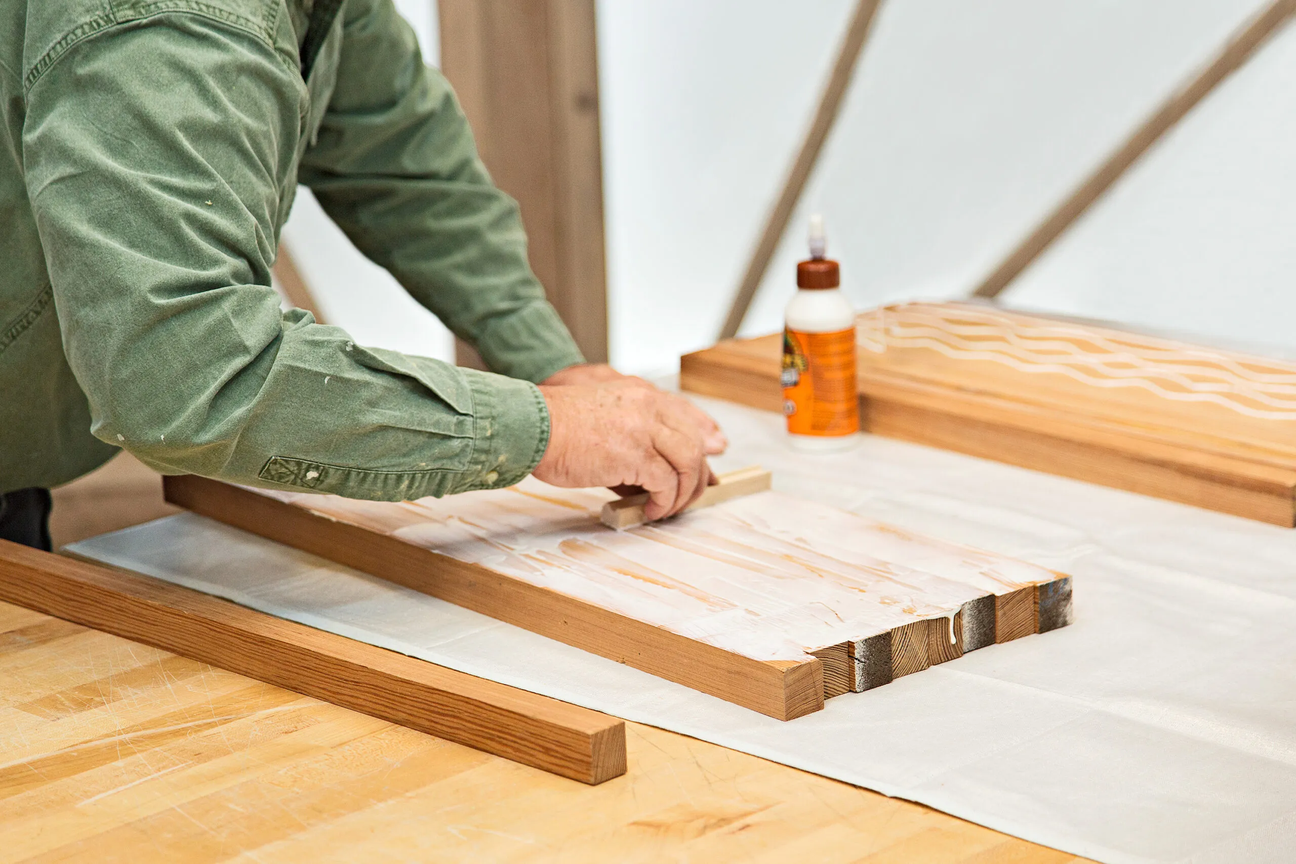 A man glues the strips of his end grain cutting board together.