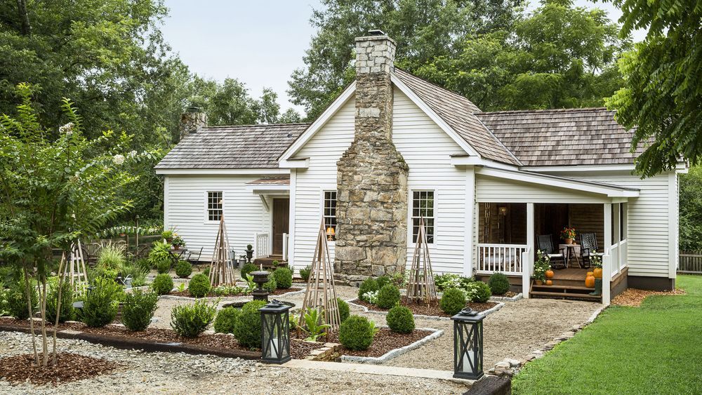 A renovated home with a garden full of bushes and trees.