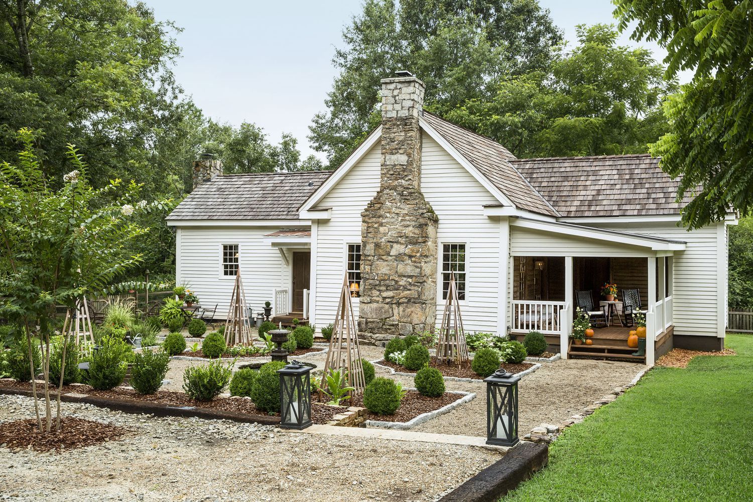 A renovated home with a garden full of bushes and trees.