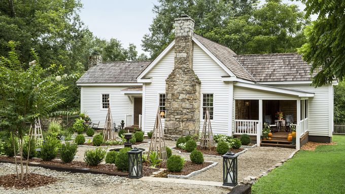 A renovated home with a garden full of bushes and trees.